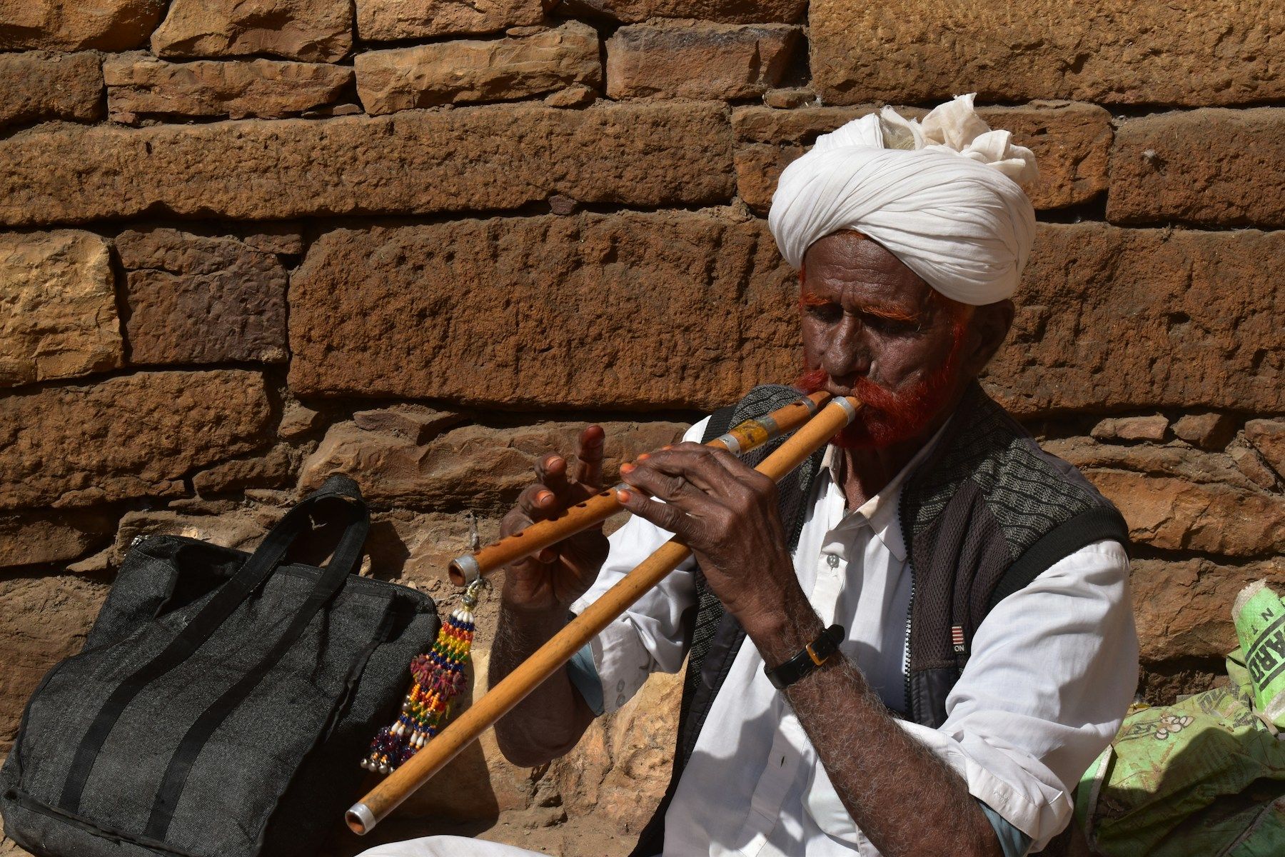 Iäkäs mies turbaanissa soittaa huilua ulkona