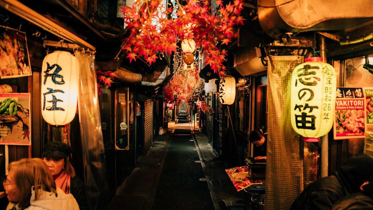 Tokion pieni kuja iltavalaistuksessa, jossa pitkä rivi perinteisiä papereilla varustettuja lyhtyjä