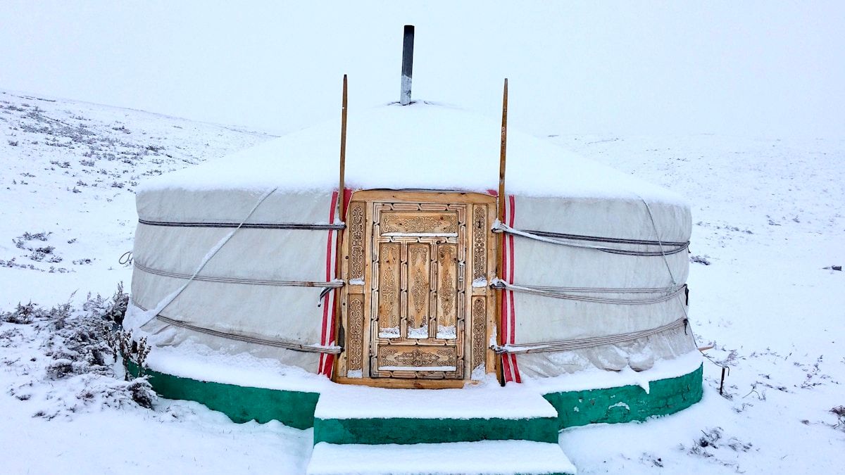 Lumisten Mongolian aroilla seisova perinteinen ger-teltta iltavalossa